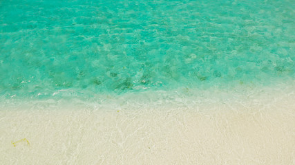Obraz premium Sandy beach with and azure water of the lagoon,copy space for text, top view. Sea water surface in lagoon. Transparent turquoise ocean water surface. Background texture