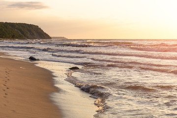 Fototapeta na wymiar sandy beach, sheer shore on the horizon and a summer sunset over the sea
