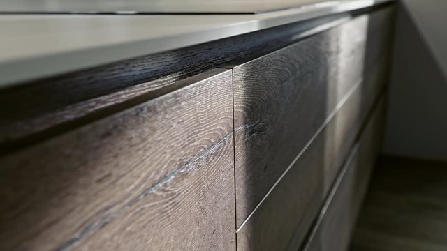 Tilting up the surface of a natural wood kitchen unit with cuoboards and drawers to the hob above in an oblique angle view in an interior decor concept