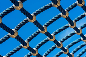 Bright blue rope mesh against a bright blue sky close-up. Background and texture