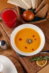 Yellow pumpkin soup with freshly baked bread and fruit drink for a perfect autumn dinner indoors