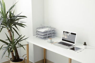 office table on which laptop, coffee, tablet, camera and other items