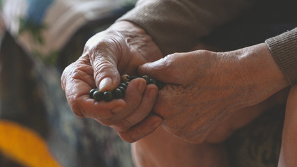 old wrinkled hands.  woman with rosary beads for praying.