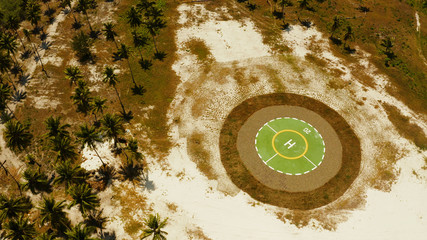 Helipad among the palm trees on a tropical island from above. Helicopter landing site. Bugsuk island, Balabac, Palawan