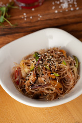 Thai noodles with vegetables, roasted chicken and sesame, flavoured with oyster sauce on wooden table with ingredients on it