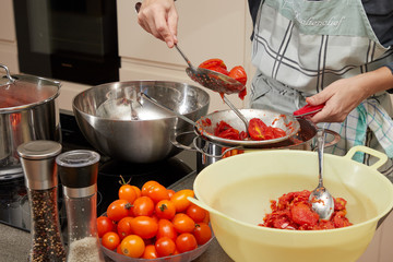 hausfrau beim tomaten einkochen in moderner küche