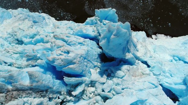 Aerial of blue ice formation on the edge of a glacier over the sea