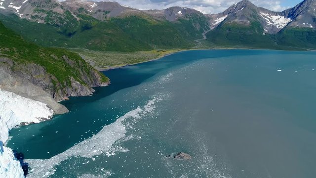 Aerial of icy water flowing away from a glacier into sea Alaska