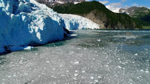 Aerial of global warming melting ice on glacier over rising sea levels water