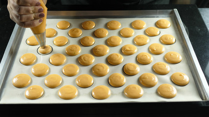 confectioner squeezes baking cream onto the mold to prepare a traditional macaroon dessert