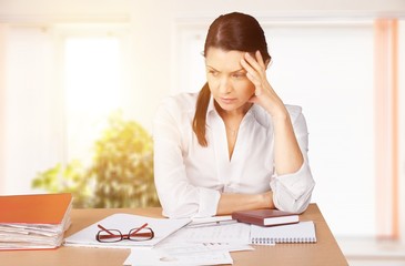 Businesswoman sitting at the table with many papers in office