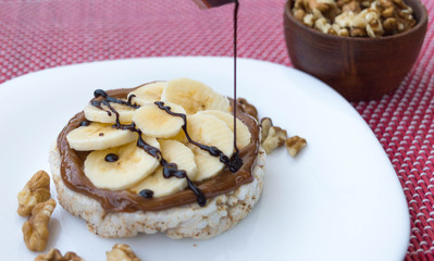 Fototapeta na wymiar Rice biscuit with dulce de leche and pieces of banana and nuts. Accompanied with a milk banana smoothie. Added low calorie chocolate.