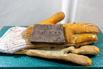 White and yellow old wore down ragged fire resistant protective working gloves on top of a green vintage metal box
