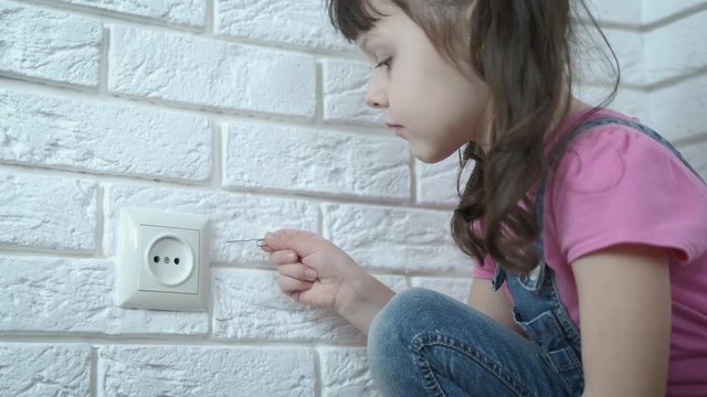 A child with electricity. A little girl without parental supervision wants to shove a wire into the socket.