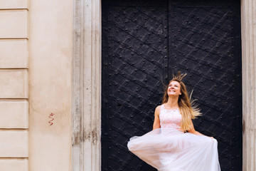 Fototapeta premium The bride in a wedding dress looks up and the wind blows a weddi