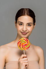 happy young woman holding colorful lollipop isolated on grey