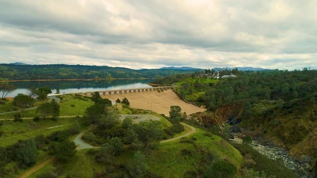 Aerial View  Dam Village waterfront  4K Helicopter Shot  landmark trees road cars cloudes california lake