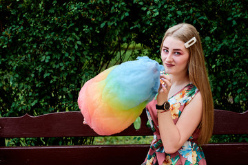 Happy joyful beautiful young woman with candy floss, spun sugar, cotton candy in the park at...