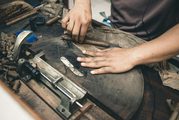 Closeup of hands making cigar from tobacco leaves. Traditional manufacture of cigars. Dominican Republic