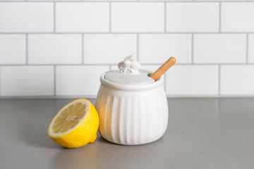 White Ceramic Honey Pot with Wooden Honey Dipper and Lemon Slice, White Subway Tile Background in Kitchen