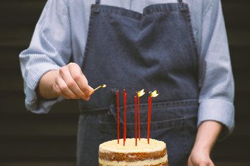 Young male hand lights the seven candles on the birthday cake