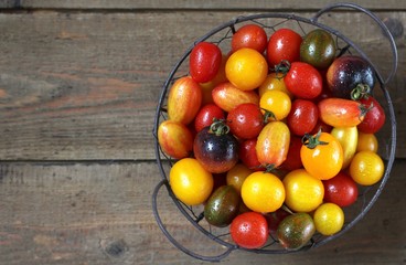 Fototapeta na wymiar cherry tomatoes are different varieties in the basket, small tomatoes of different colors and types.