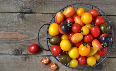 cherry tomatoes are different varieties in the basket, small tomatoes of different colors and types.