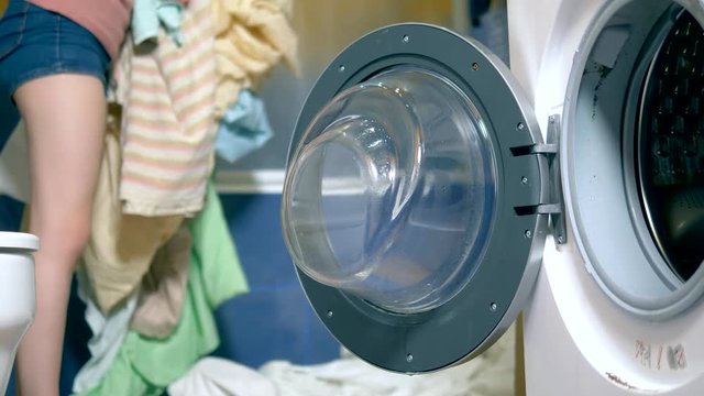 concept of washing at home. woman puts laundry in the washing machine