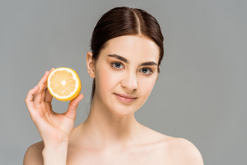 attractive naked girl holding half of lemon isolated on grey