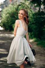 Gorgeous young model woman with perfect  hair looking at camera posing in the city wearing  evening dress.