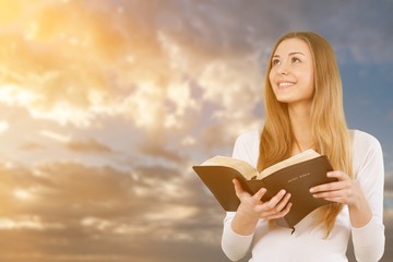 Happy Young Woman Praying with Bible in hands