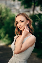 Obraz premium Gorgeous young model woman with perfect hair looking at camera posing in the city wearing evening dress.