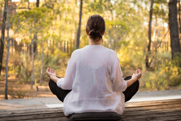 Una mujer practica la meditación, en un entorno natural, durante la puesta de sol