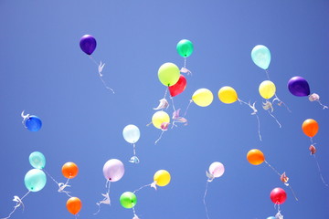 Colorful balloons with paper pigeons tied to them fly in the blue sky