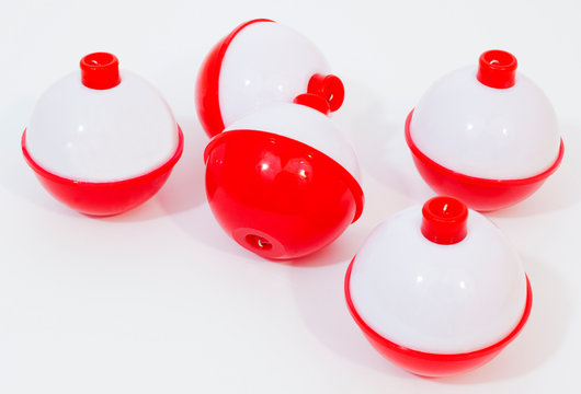 Several red and white fishing bobbers on a white background.