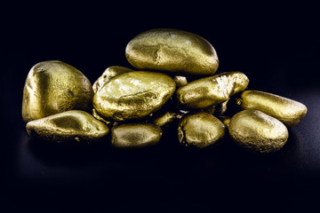 Gold nugget, large gold stone closeup isolated on black background. Concept of finance, luxury or wealth.