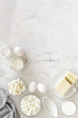 Fototapeta na wymiar Fresh dairy products for breakfast with milk, cottage, eggs, butter, yougurt on white marble background top view mock up
