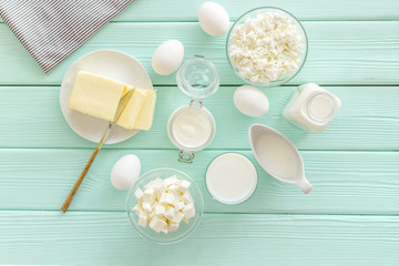 Fresh dairy products with milk, cottage, eggs, butter, yougurt on mint green wooden background top view