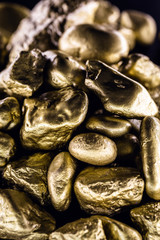 Gold nugget, large gold stone closeup isolated on black background. Concept of finance, luxury or wealth.