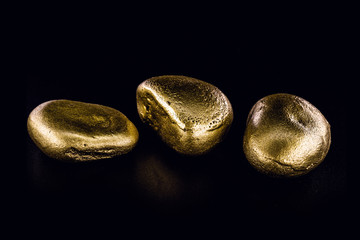 Gold nugget, large gold stone closeup isolated on black background. Concept of finance, luxury or wealth.