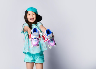 Little happy smiling asian baby girl kid in light blue t-shirt and hat cap shows demonstrates her...
