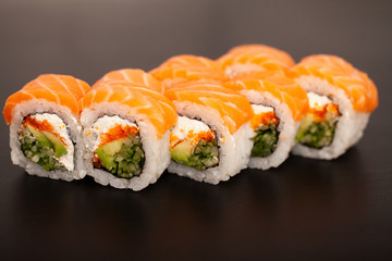 Sushi roll with salmon, cheese and avocado.