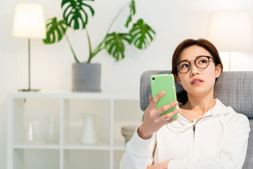 部屋でスマホを見る女性　考える