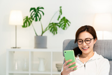 部屋でスマホを見る女性　
