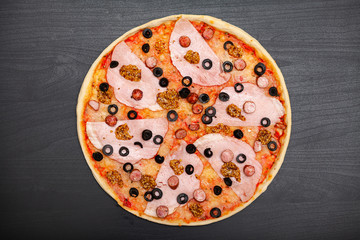 Tasty pizza with various flavored ingredients on a dark background