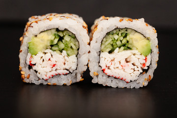 Japanese Sushi roll with salmon and cucumber on dark background.