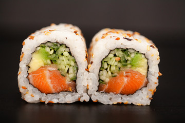 Japanese Sushi roll with salmon and cucumber on dark background.