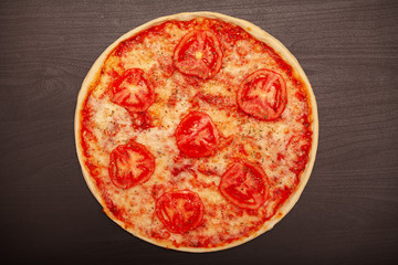 Tasty pizza with various flavored ingredients on a dark background