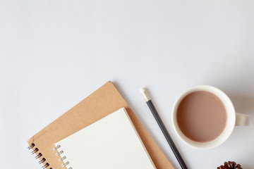 Flat lay of paper notebook, pencil, cup of coffee with copy space on white background. Top view of office desk. minimal style.