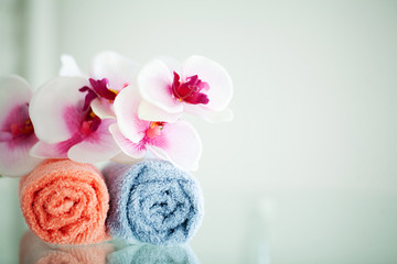 Obraz na płótnie Canvas Colored towels and orchid on white table with copy space on bath room background